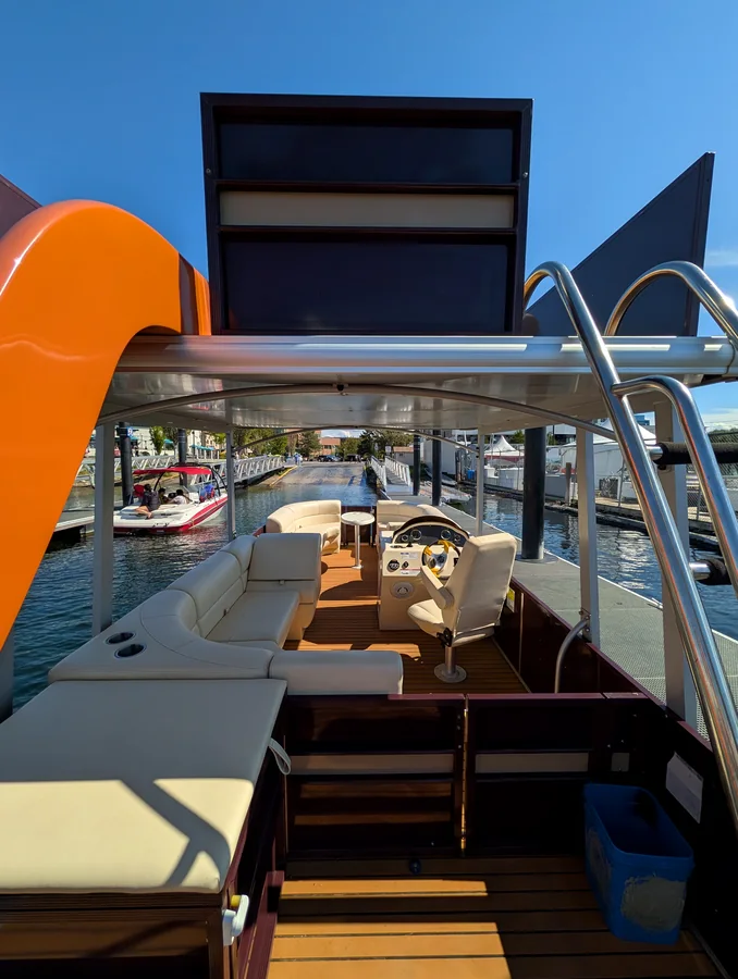 Shaded lower deck of the pontoon boat with wraparound seating and the helm
